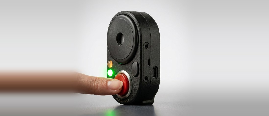 The Vigil SOS device, with a finger pressing its emergency call button